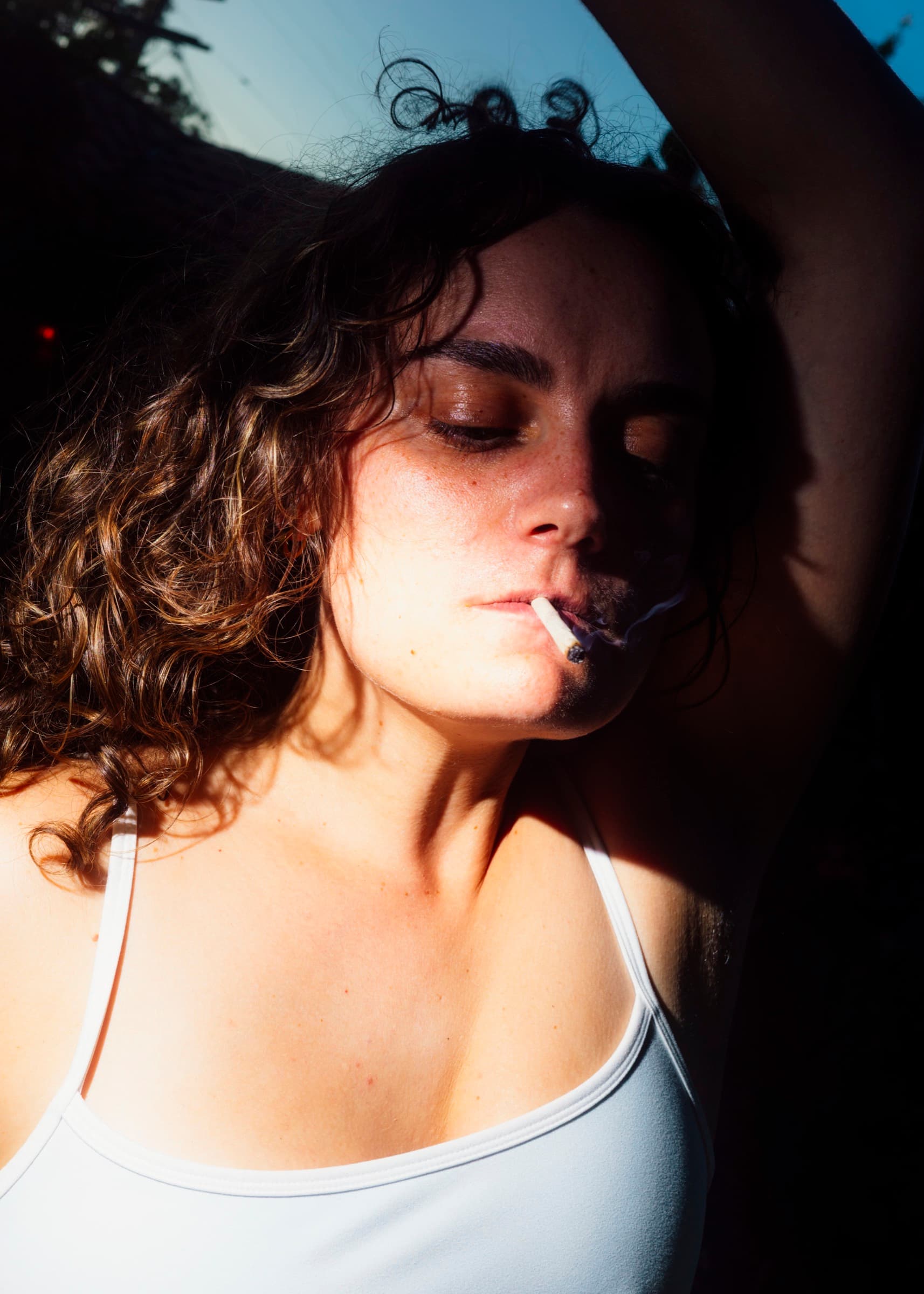 A person with eyes closed, smoking a joint in the sun